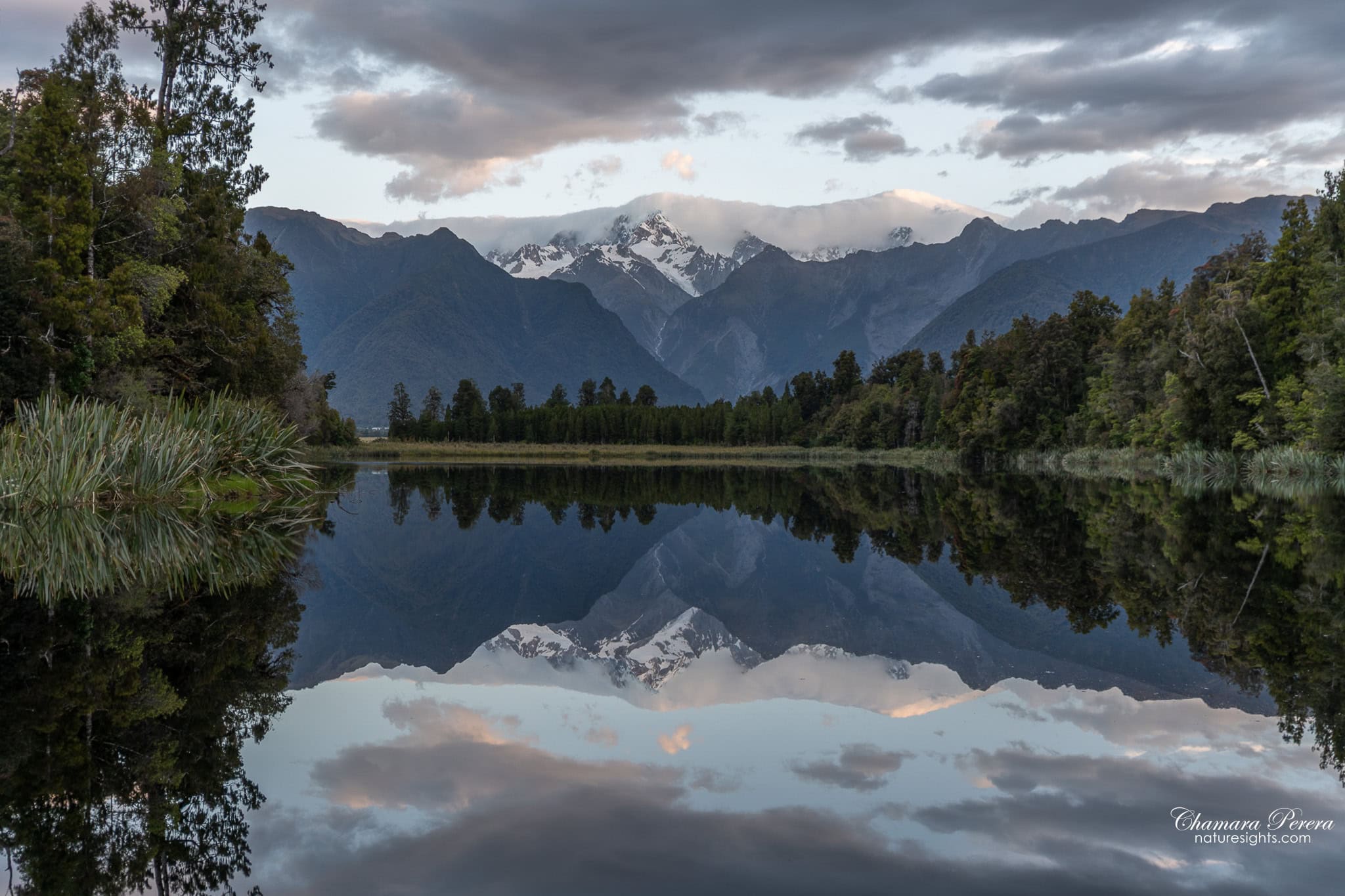 Wide reflection of forest and Southern Alps in Lake Matheson New Zealand