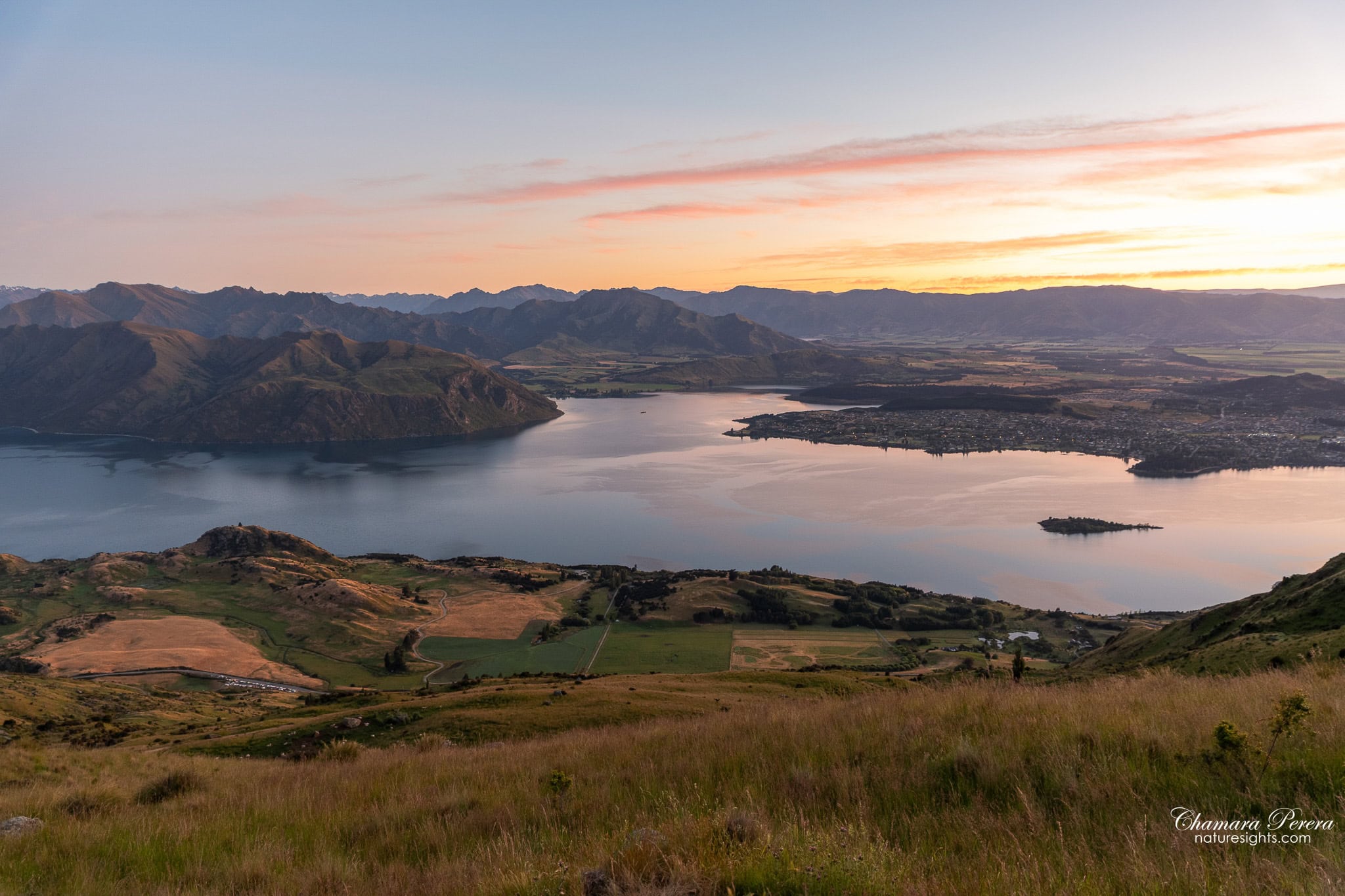 Wide panorama of Lake Wanaka in pink dawn light from Roy's Peak New Zealand