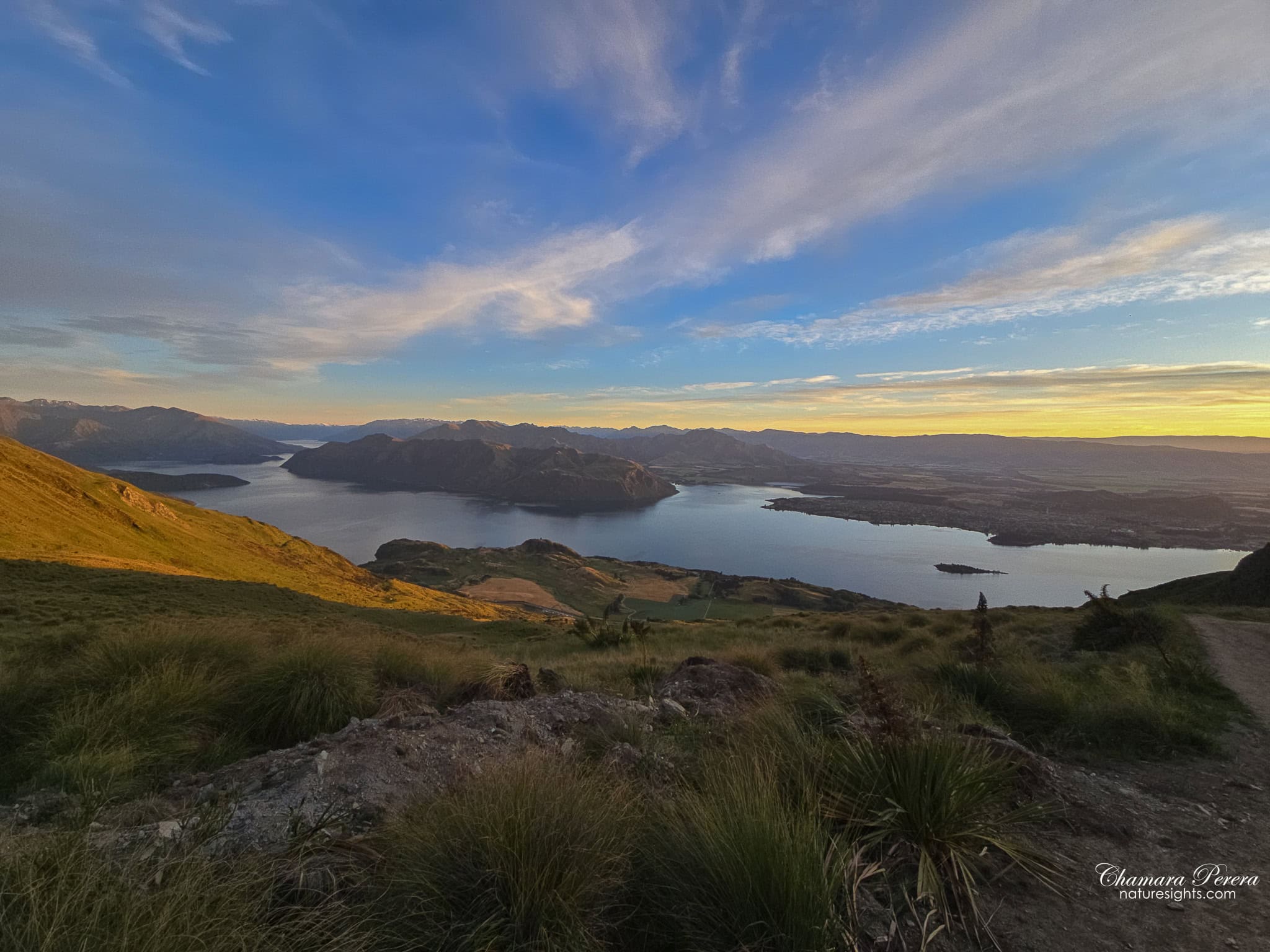 Lake Wanaka at sunrise from Roy's Peak trail with rocky foreground New Zealand