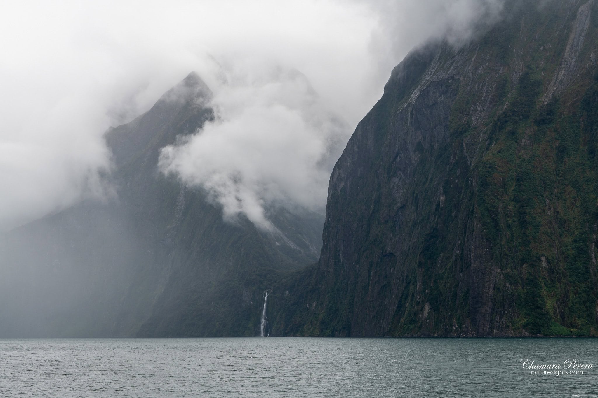 Milford Sound cliff with distant waterfall and cloud Fiordland New Zealand