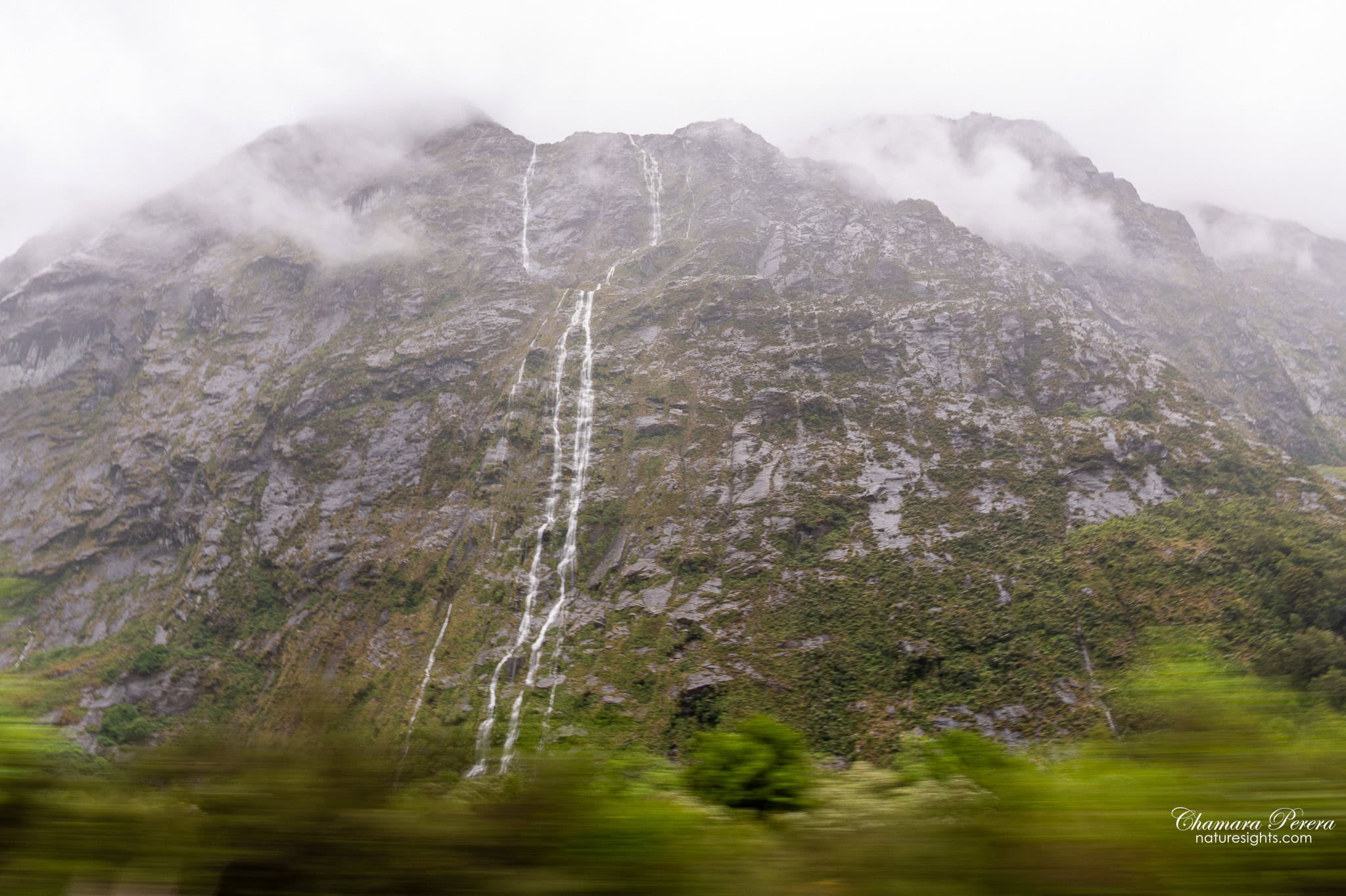 Multiple waterfalls on mountain face on the drive to Milford Sound Fiordland New Zealand