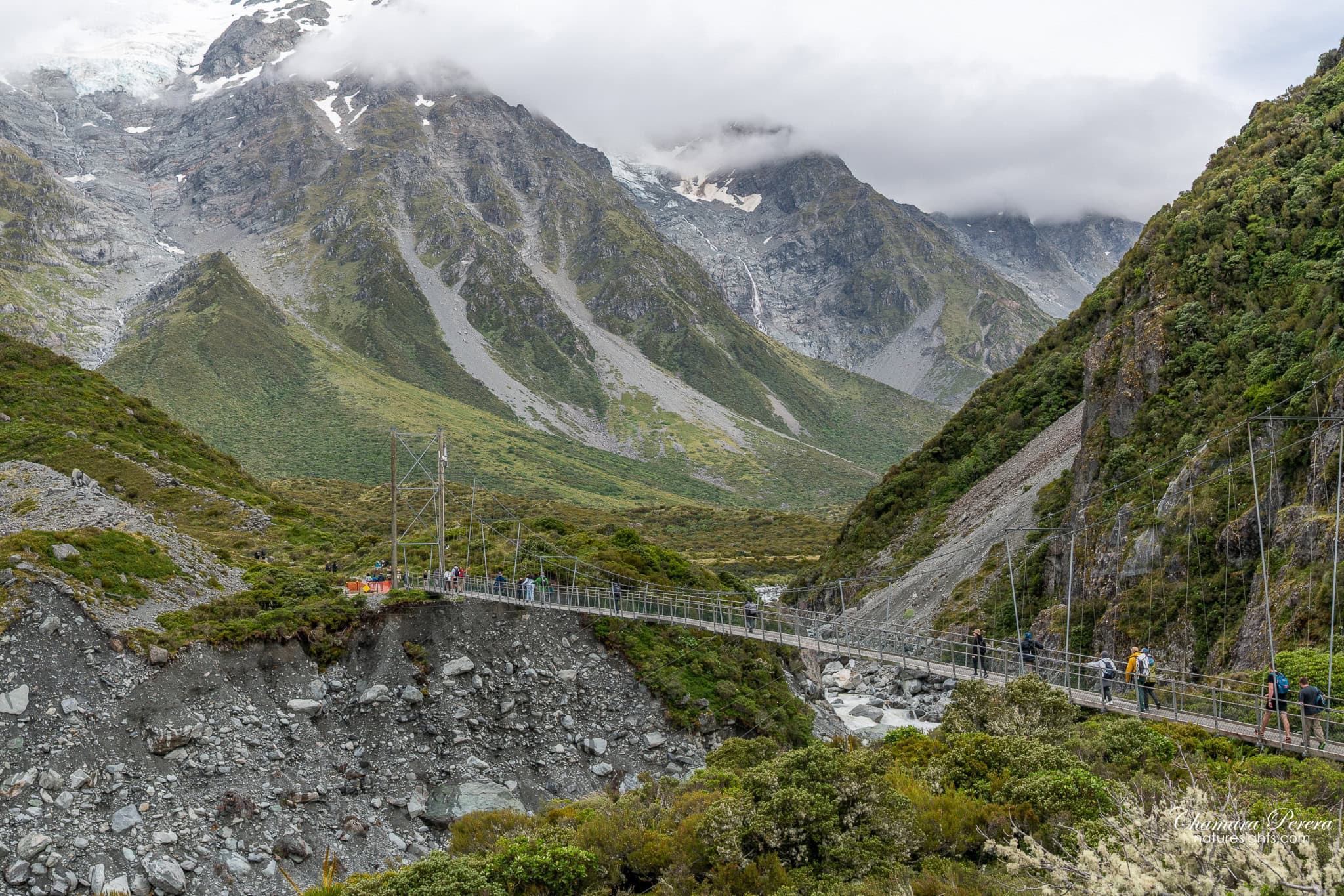 swing bridge with people crossing Hooker Valley Track Mount Cook New Zealand