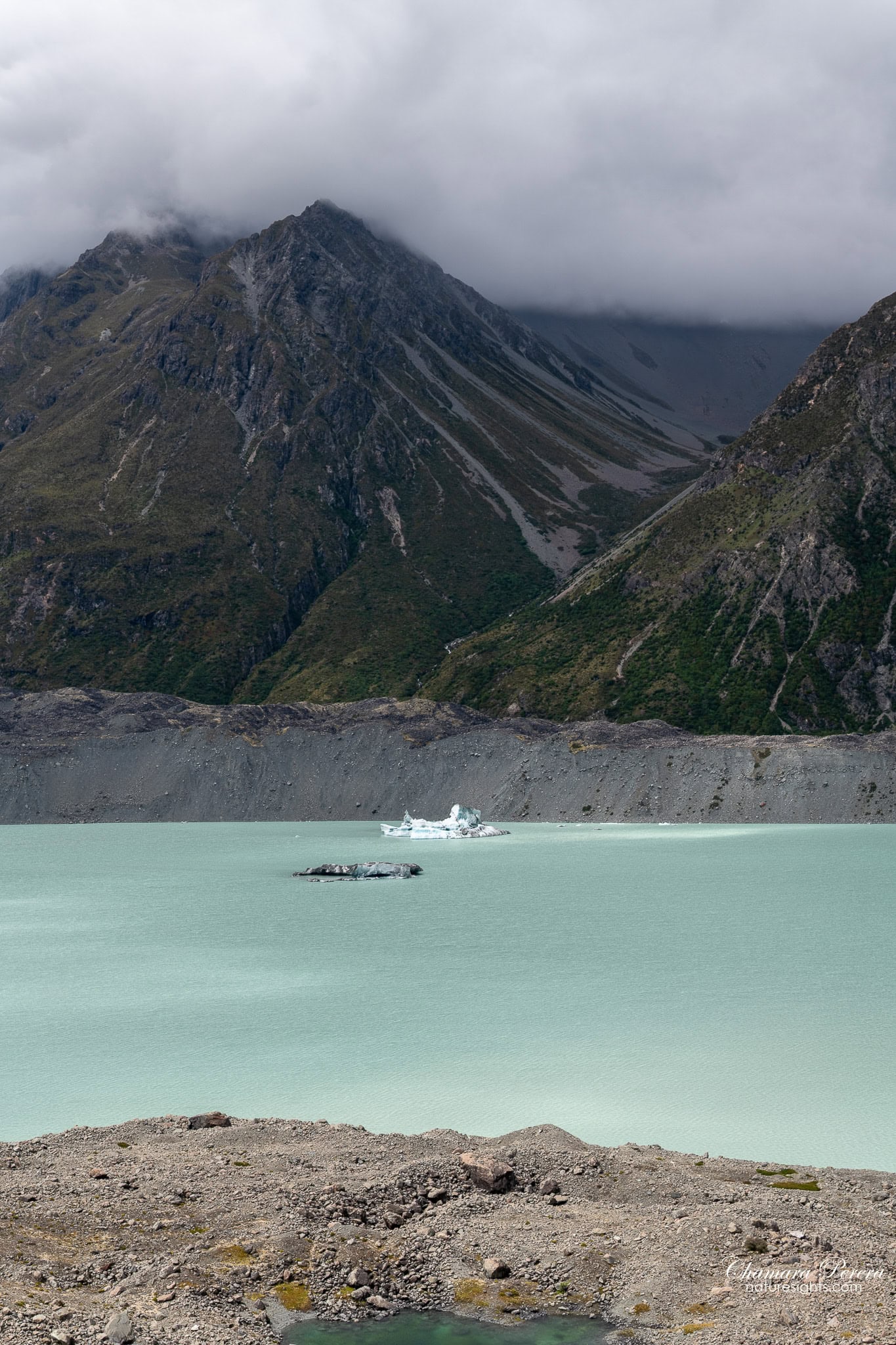 Tasman Lake with iceberg framed between moraine walls and mountain peaks Mount Cook New Zealand