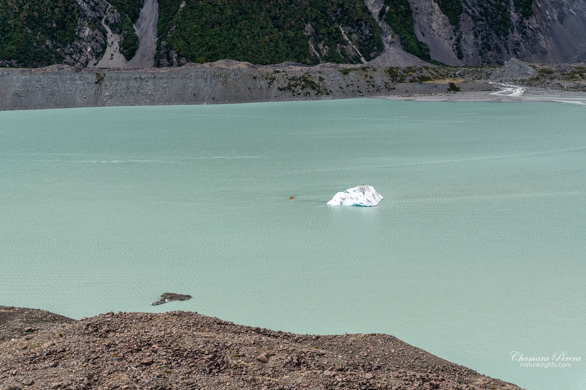 Zodiac boat approaching iceberg on Tasman Lake with moraine walls Mount Cook New Zealand